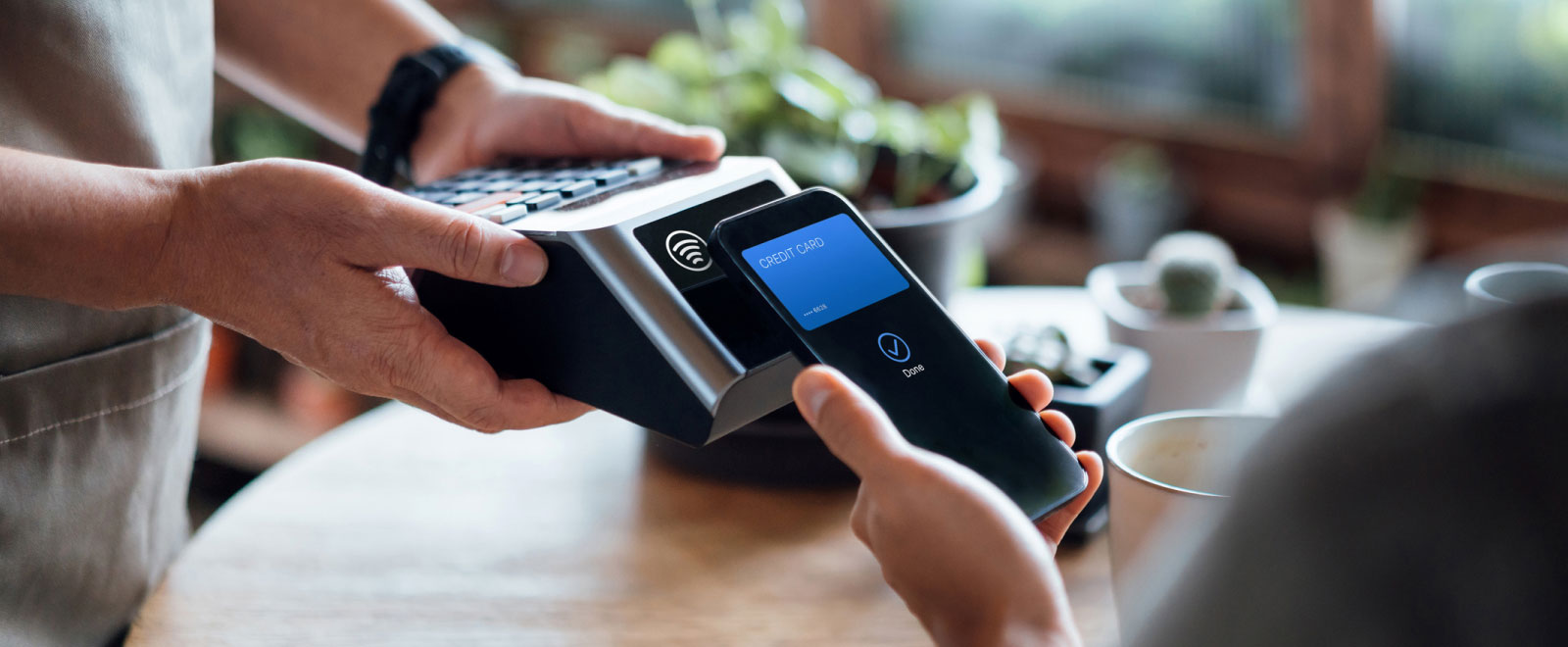 close-up of someone holding a smartphone up to a payment processor