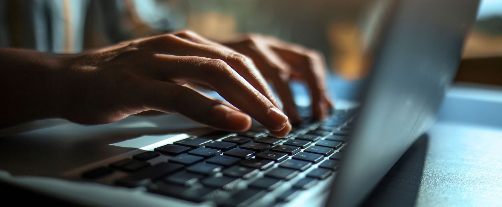 close-up of hands typing on a laptop keyboard